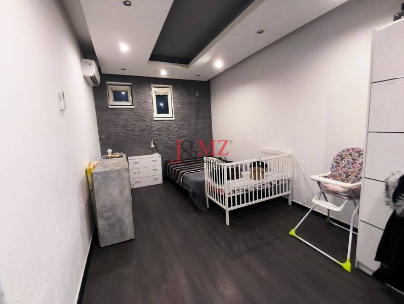 Children's room in a family house with a wooden decor floor and a wall with stone cladding.