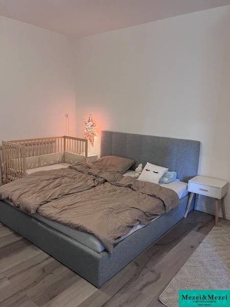 Bedroom with an upholstered bed, a baby crib, and a nightstand in a 4-room apartment.