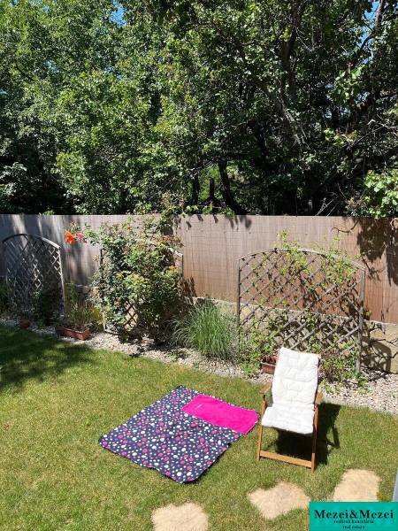 Garden of a 4-room apartment in Bratislava - Vrakuňa with a chair and a carpet on the grass.