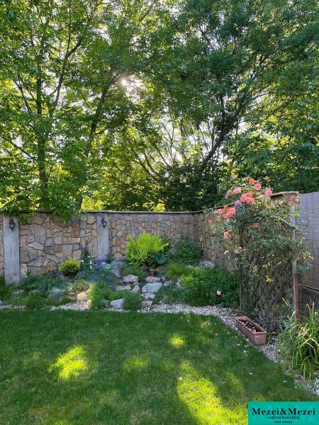 Garden of a 4-room apartment in Bratislava - Vrakuňa with a lawn and a stone wall.