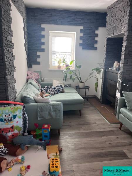 Living room with a green sofa, toys, plants, and walls with stone cladding in a 4-room apartment.