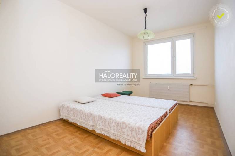 A bedroom in a 3-room apartment with a wooden decor floor, a bed by the window.