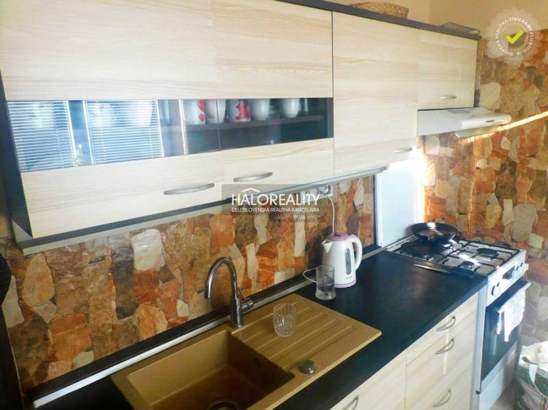 A room in a 2-room apartment with a wooden decor floor, a television, and built-in wardrobes.