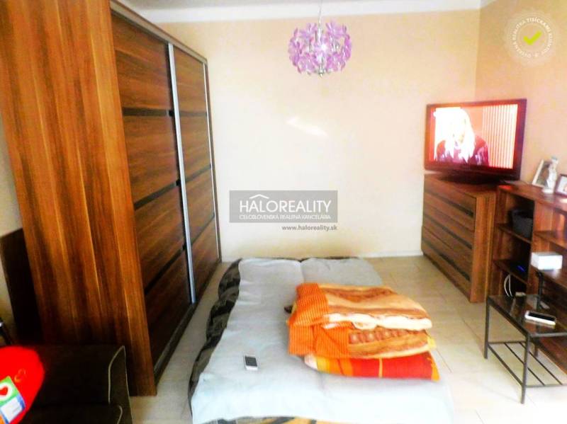 A bedroom in a two-room apartment with a bed, sofa, and cabinet with a wooden decor.