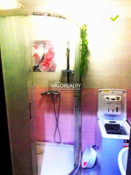 A bathroom in a 2-room apartment with a shower and a washing machine, color-coordinated in pink.