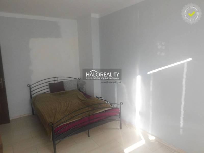 A bedroom with a metal bed and white walls in a two-room apartment.