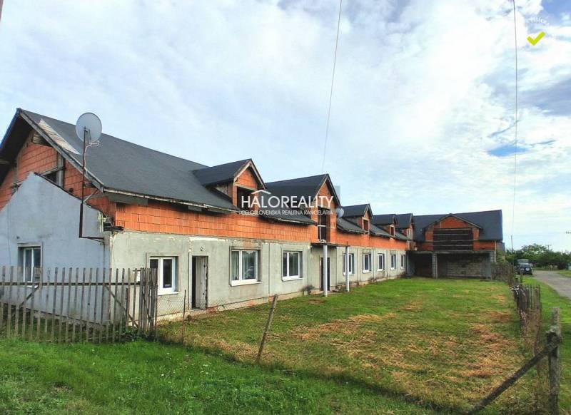 Commercial premises in Tibava, an unfinished building with a grassy area and a fence.