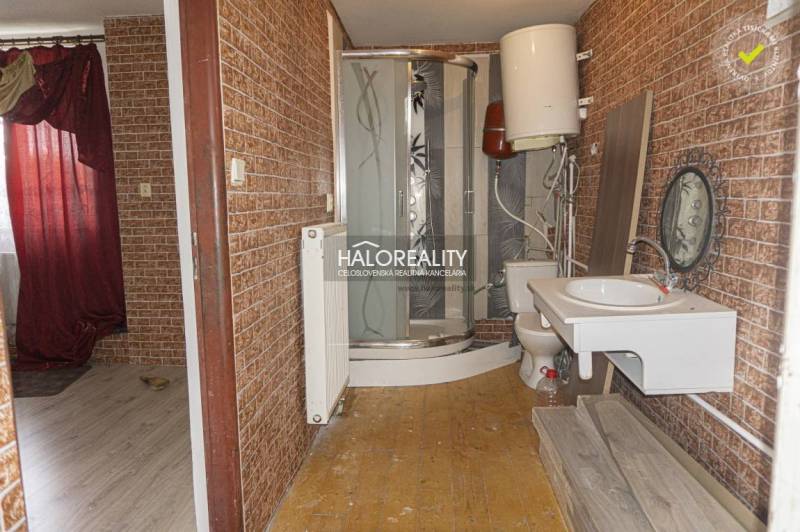 A bathroom in commercial premises with wooden decor on the walls and a shower enclosure.