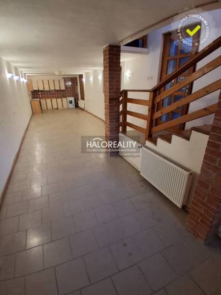 Interior in a family house with tiles, wooden staircase, and kitchen unit.