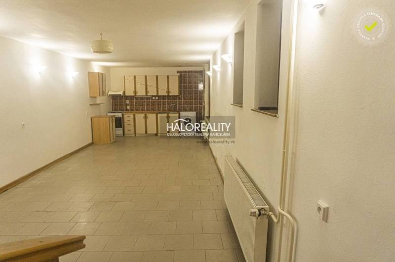 Spacious kitchen and dining room in a family house with tiles and bright lighting.