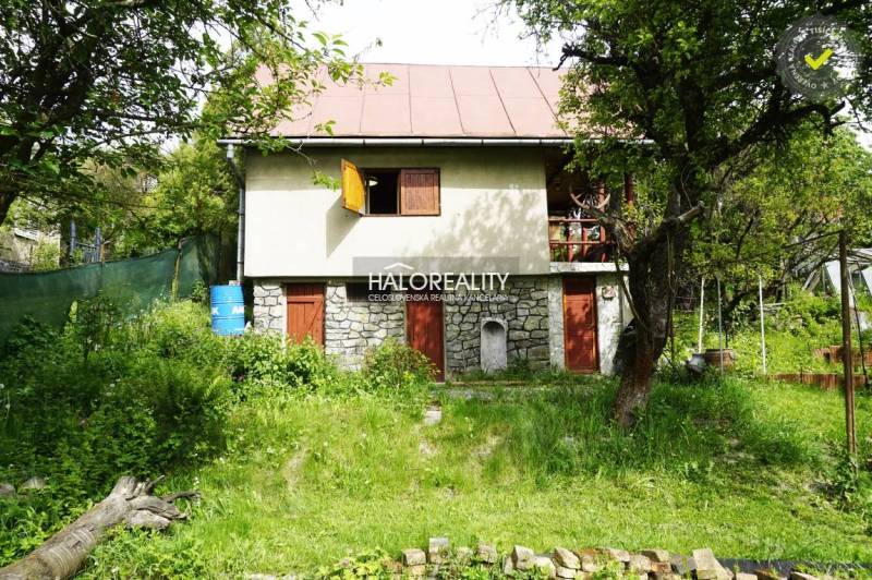 A cozy cottage surrounded by lush greenery and trees in a natural setting.