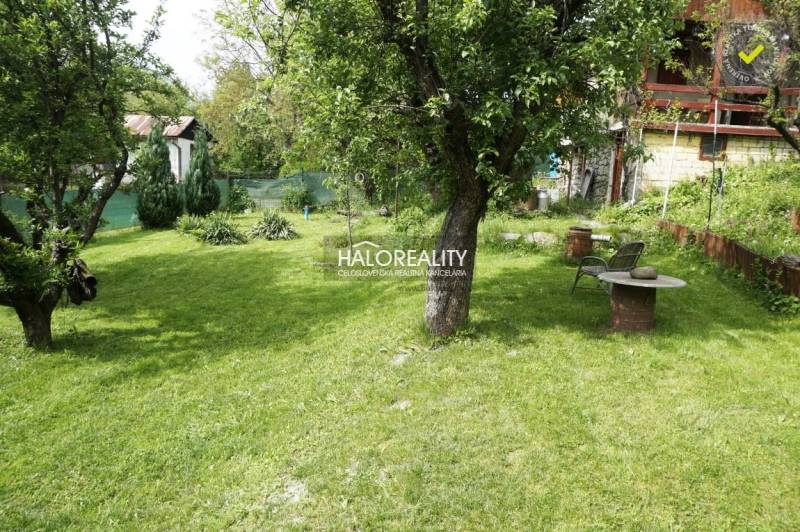 Garden and cottage with a gazebo, lawn, trees, table and chairs, ideal for relaxation.