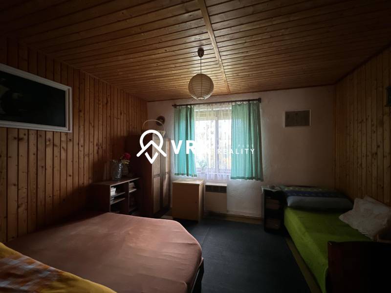 A room with wooden paneling and beds in a family house.