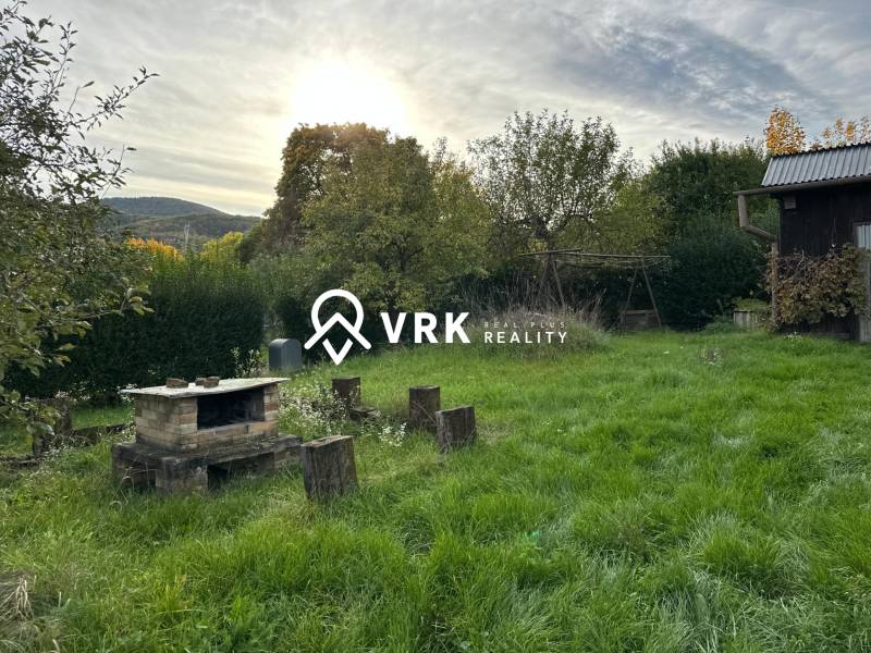 The garden of a family house in Kalša with a fireplace and greenery in the background.
