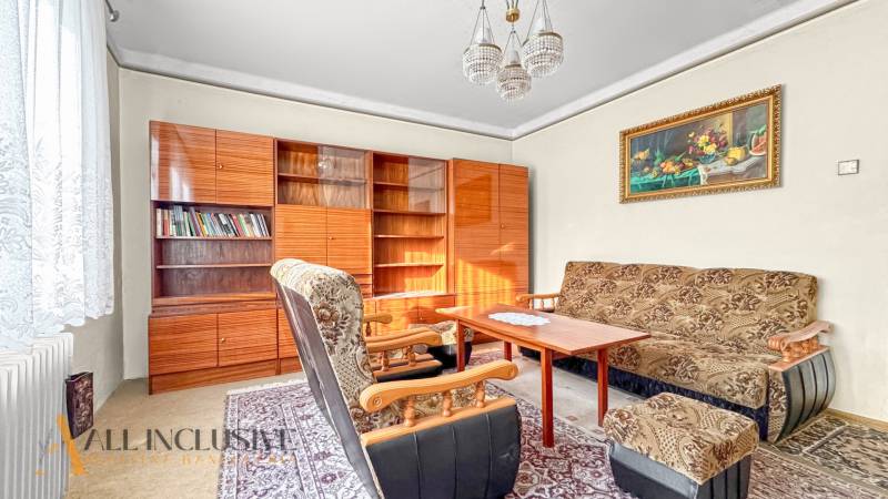 Living room in a family house with armchairs, carpet, bookshelf, and curtains.