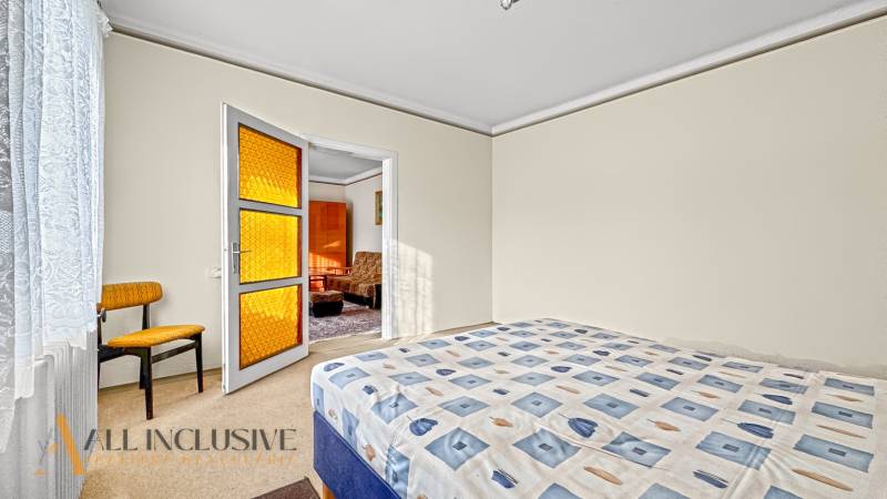 Bedroom in a family house with a bed, chair, and door with orange glass.