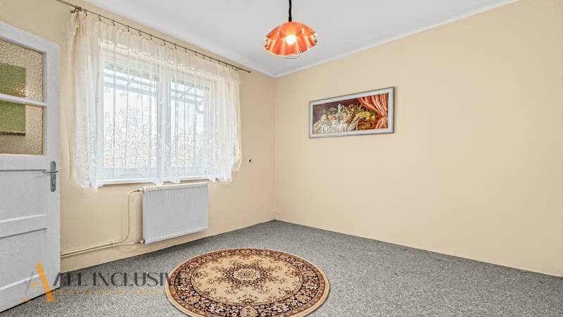 A room in a family house with a light carpet, curtains, and a wall painting.