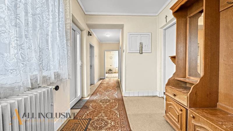 A hallway in a family house with wooden furniture and a carpet.