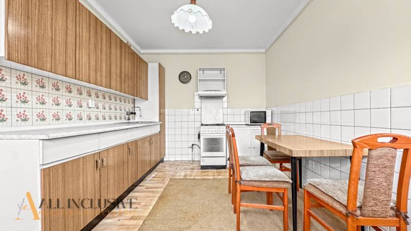 A kitchen in a family house with a kitchen unit, a table, and retro tiles on the walls.