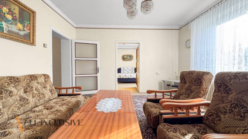 A family house with a living room, floral furniture, a coffee table, and a painting on the wall.