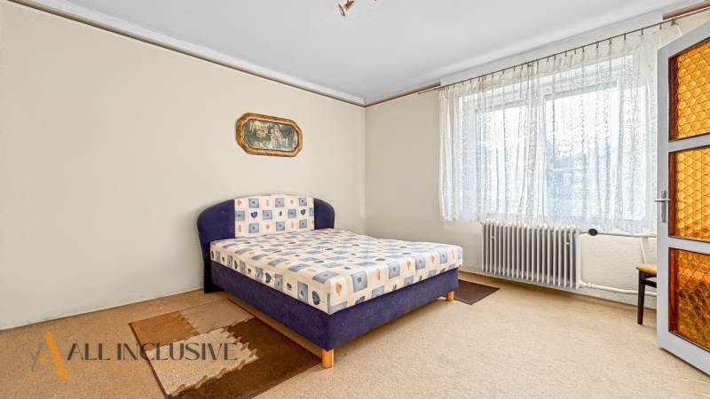 Bedroom in a family house with carpet, large window, and radiator.