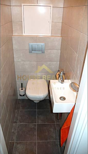 Small bathroom with a toilet and a sink in a 4-room apartment. Gray tiles and flooring.