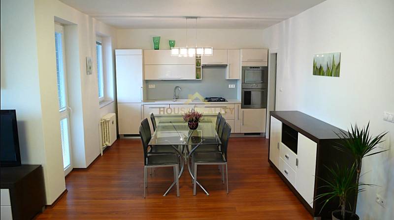The kitchen of a 4-room apartment with a dining table and a wooden decor floor.
