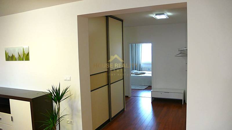 Interior of a 4-room apartment with a wooden decor floor and entrance to the bedroom.