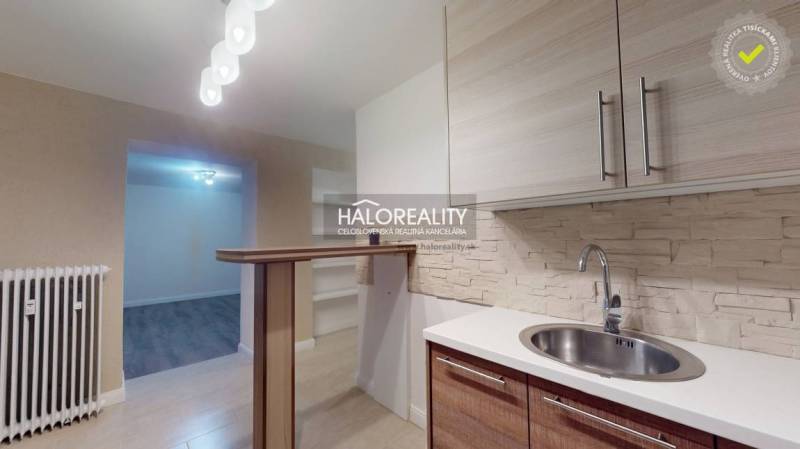 The kitchen of a two-room apartment with a wooden decor floor and a bar counter.