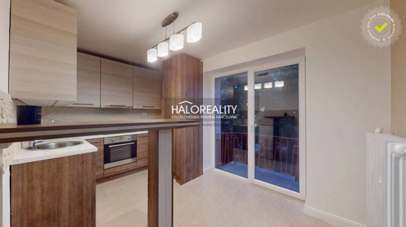 A kitchen in a 2-room apartment with a wooden decor floor and access to a balcony.