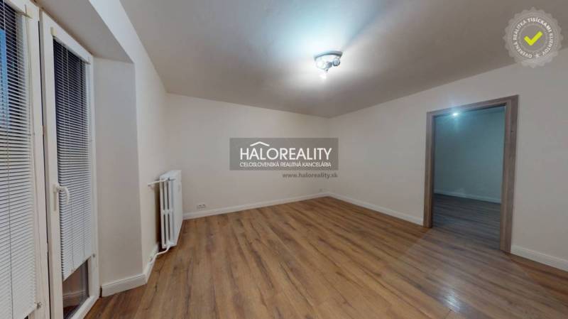 A spacious room in a 2-room apartment with a wood-patterned floor and a radiator.