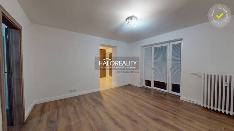 Living room in a two-room apartment with a wooden decor floor and a French window.