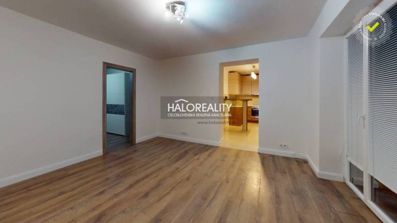 Living room in a two-room apartment with a wooden decor floor and an entrance to the kitchen.