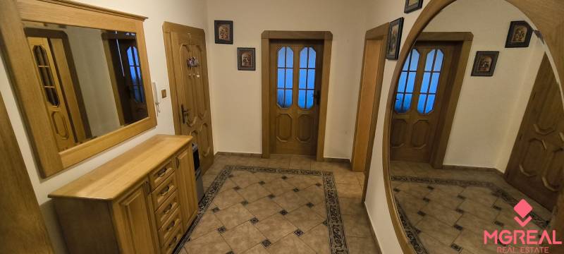 A hallway in a 3-room apartment with a mirror, tiles, and wooden furniture.
