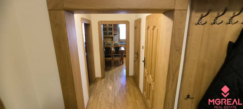 A hallway in a 3-room apartment with a wooden decor floor and coat hooks.