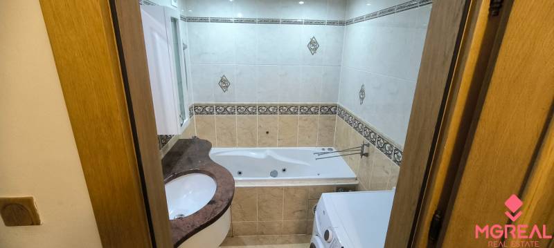Bathroom in a 3-room apartment with a bathtub and a washing machine, decorative tiles.