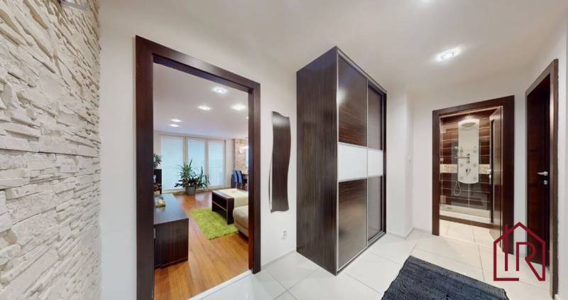 A hallway of a 3-room apartment with a wooden decor floor and stone cladding on the wall.