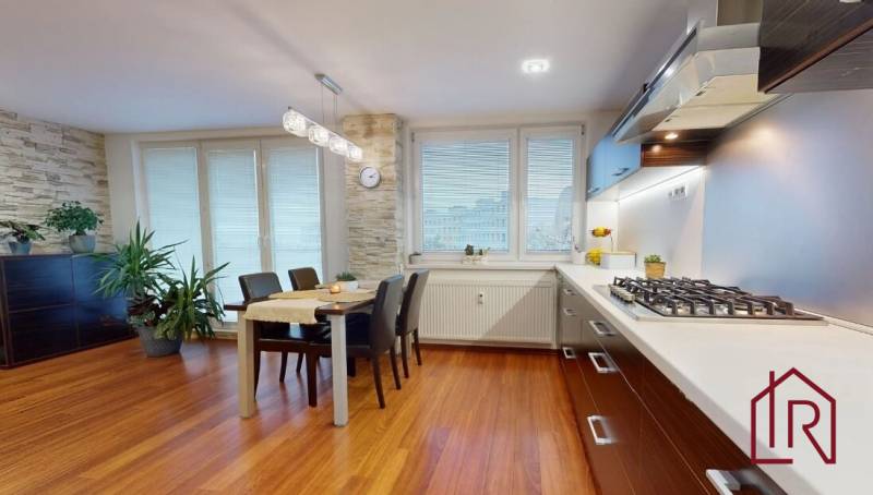 A kitchen in a 3-room apartment with a wooden decor floor, a dining table, and plants.