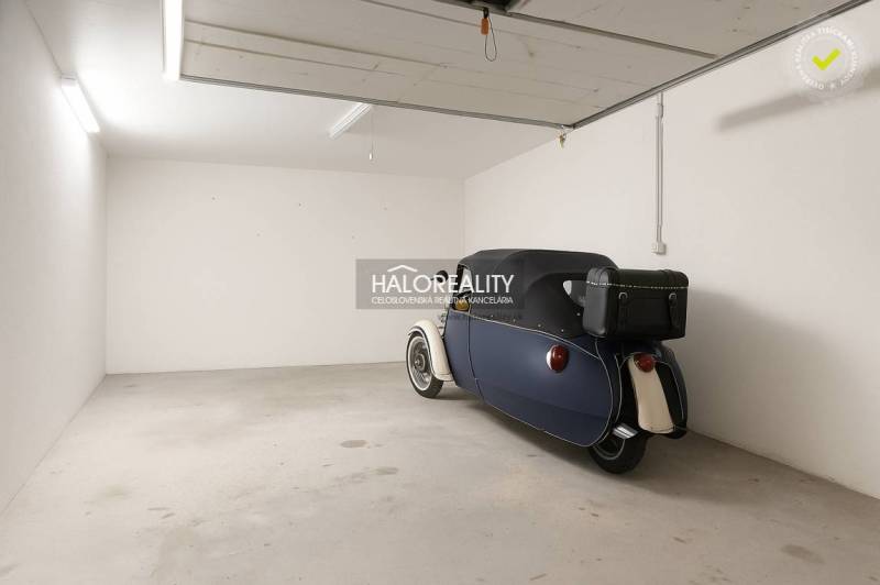 A garage in Borčice with a parked retro vehicle, smooth concrete floor, white walls.