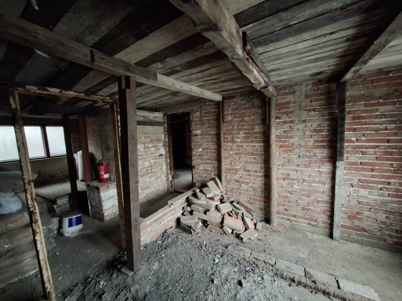 Unfinished interior with brick walls and wooden ceiling in a family house.