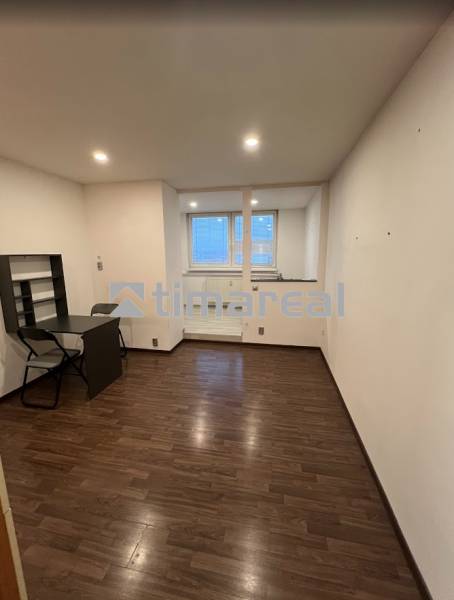 A room in a one-room apartment with a wooden decor floor and a table.