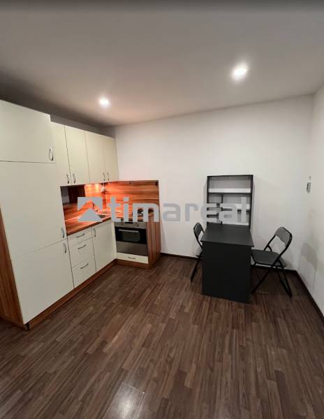 A kitchenette with a table in a studio apartment and a floor with a wooden decor.