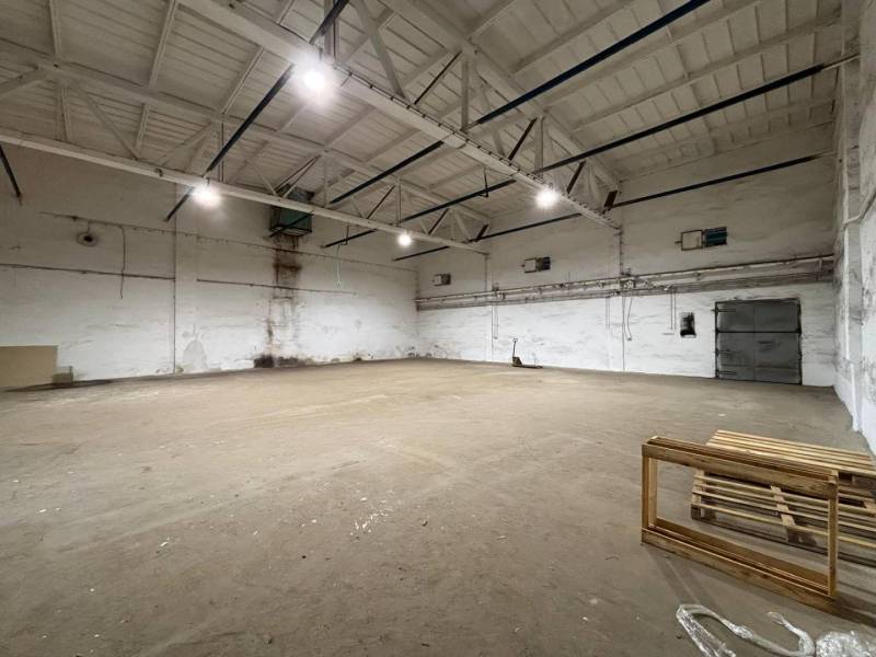 Industrial hall with high ceiling, lighting and empty space, suitable for offices.