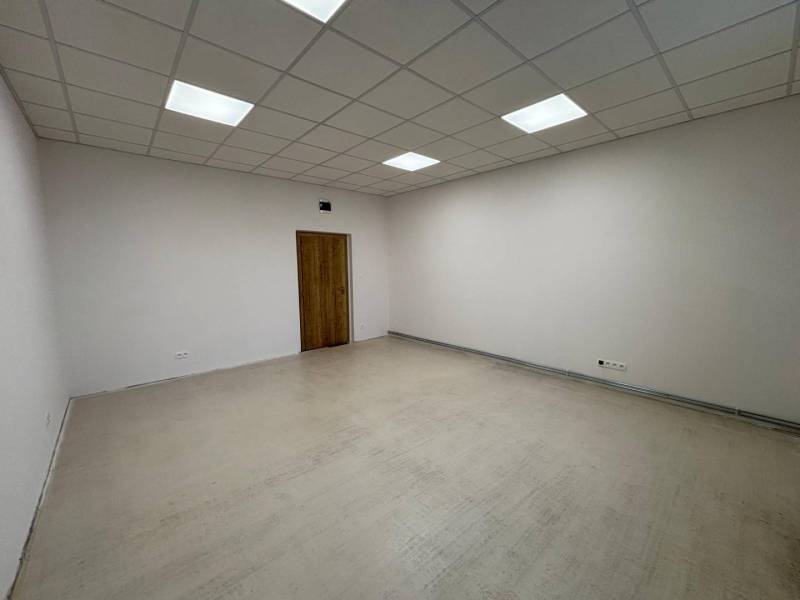 Empty room in offices with wood-patterned flooring and white walls.