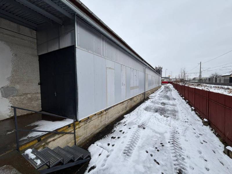 A snow-covered area with offices in Poprad, next to the tracks and a metal fence.