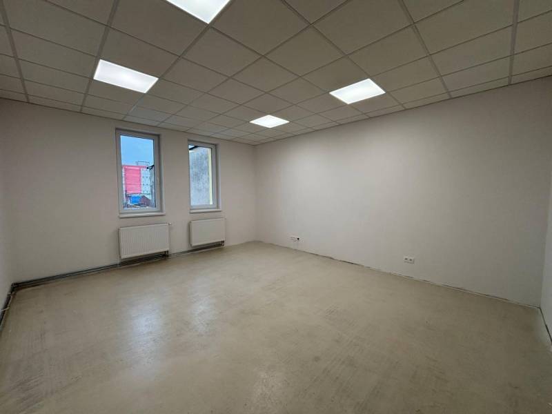 An empty office with white walls and ceiling panels, without flooring with a wooden decor.