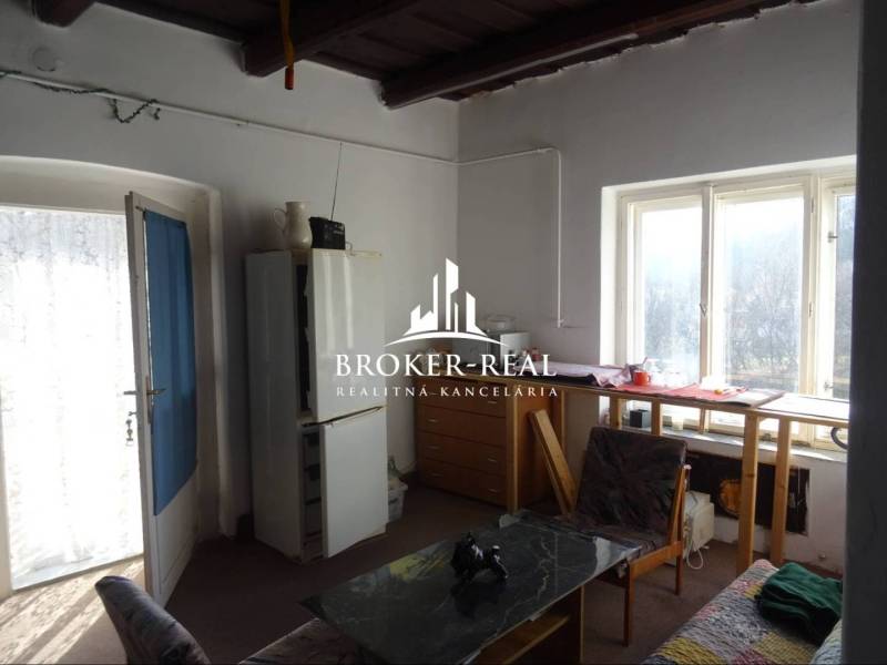 A room in a family house with a lit table by the window, an armchair, and a dining table.