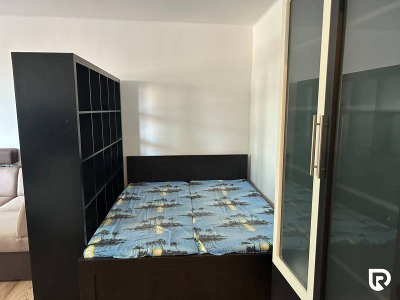 Bedroom in a studio apartment with a bed and storage cabinets.