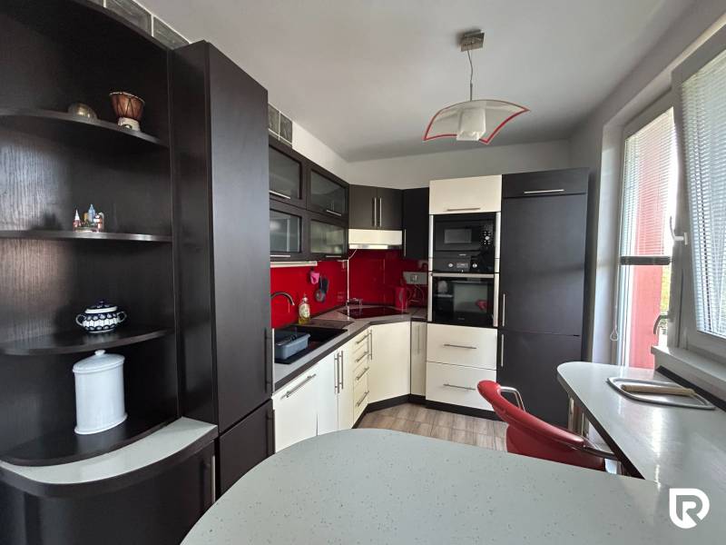 A kitchen in a studio apartment with a wood-patterned floor and red tiles.
