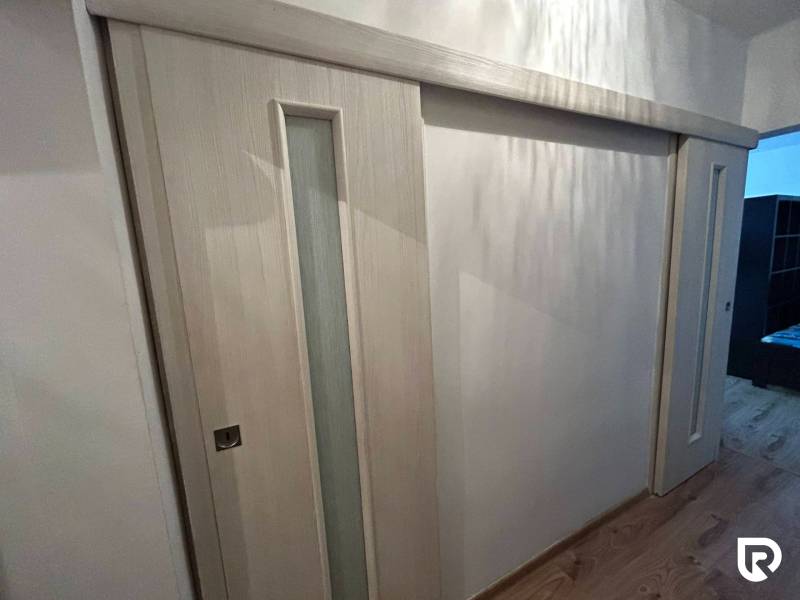 Sliding doors with glazing, floor with wood decor, interior of a studio apartment.